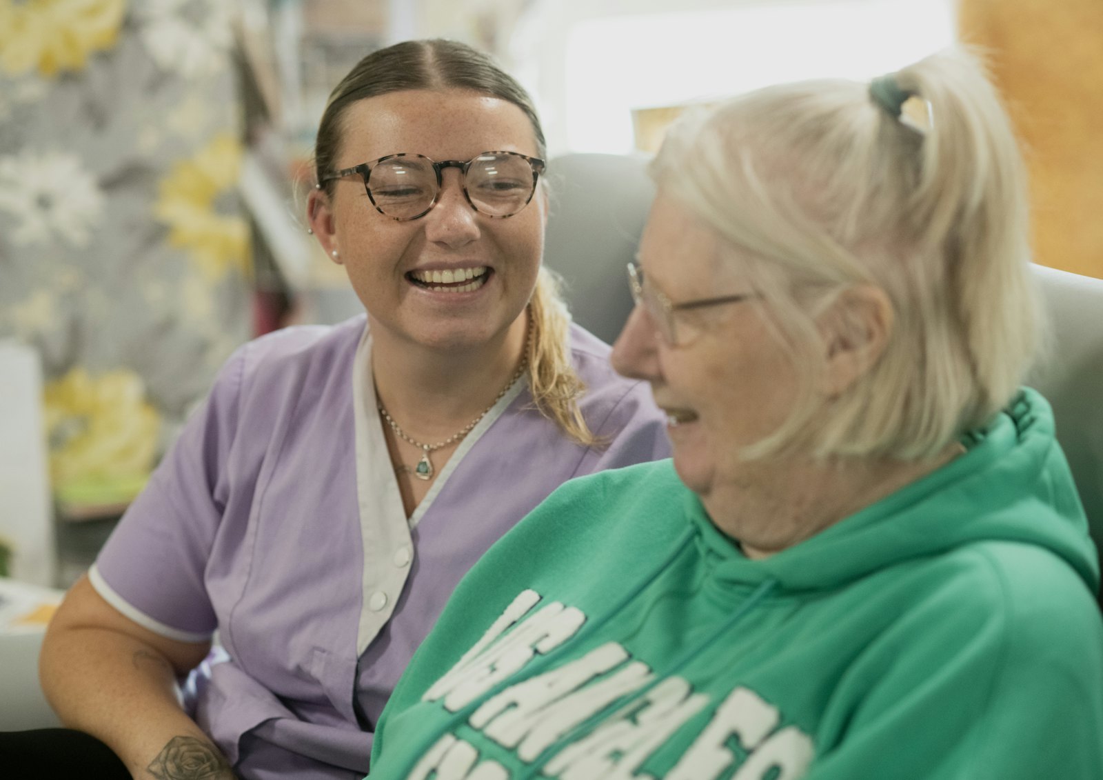 A caregiver and a resident laughing together in a skilled nursing facility.